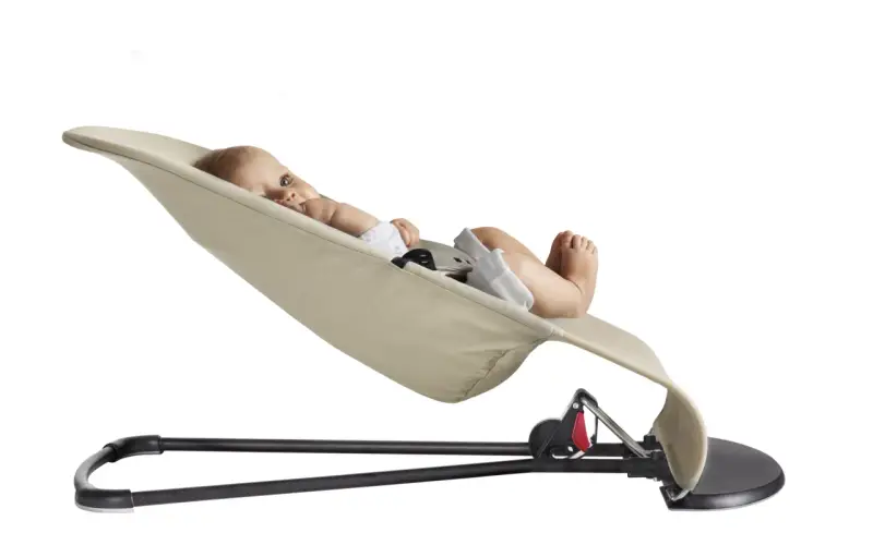 En bebis ligger bekvämt i en beige Babybjörn Balance Soft.